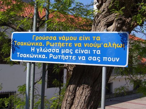 Tweetalig bord (Tsakonisch-Grieks) in Leonidio - foto: Miko (GNU) <http://commons.wikimedia.org/wiki/File:Leonidio-Tsakonian-sign.jpg>